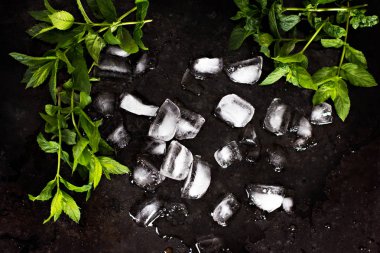 Buz küpleri ve nane yaprakları koyu arka plan üzerinde.