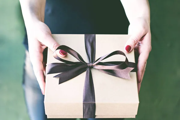 Las manos femeninas sostienen una caja hecha a mano con un regalo . — Foto de Stock