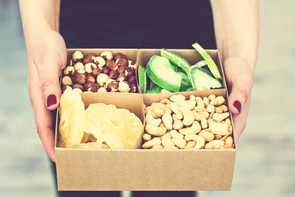 Female hands hold a box of nuts and dried fruits. — Stock Photo, Image