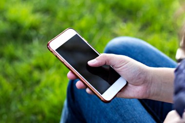 Bir şezlong nehrin arka planı kadının elinde cep telefonu. Telefon, şezlong, Yeşil çimenler, nehir. Dinlenme zamanı. Tatil, doğada telefon üzerinde çalışmak.