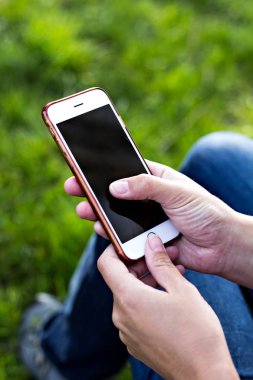 Bir şezlong nehrin arka planı kadının elinde cep telefonu. Telefon, şezlong, Yeşil çimenler, nehir. Dinlenme zamanı. Tatil, doğada telefon üzerinde çalışmak.