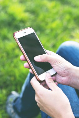 Bir şezlong arka planı yeşil çim kadının elinde cep telefonu. Dinlenme zamanı. İş dinlenme tatile bir akıllı telefon kullanan kadın, yalan ayakları kızlar, açık havada, park, yaz