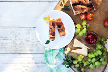 Peynir ve kurutulmuş domates ile meyveli turta. Akşam yemeği için sofrayı. Öğle Yemeği. Ev yapımı pasta, turta ve aperatifler, sebze, meyve, peynir.