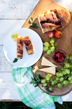 Peynir ve kurutulmuş domates ile meyveli turta. Akşam yemeği için sofrayı. Öğle Yemeği. Ev yapımı pasta, turta ve aperatifler, sebze, meyve, peynir.