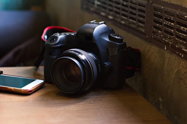 The camera and the phone on the table in the cafe.