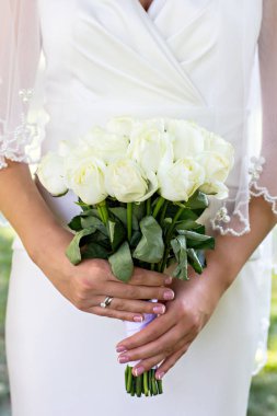 Ellerinde bir buket beyaz gül.