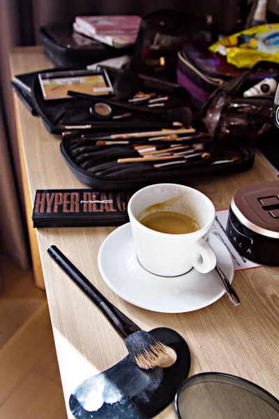 different cosmetics, many cosmetics, make-up artist table and a cup of coffee