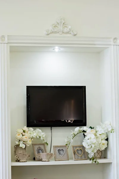 TV and a shelf under it with photos and orchids — Stock Photo, Image