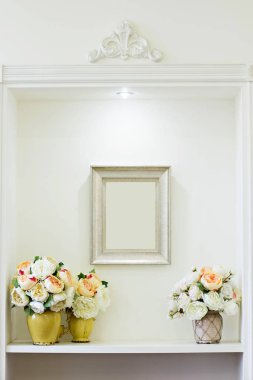 Vazoda pembe ve beyaz şakayıklar ve bir resim.