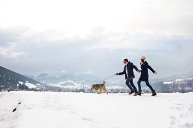 Çiftler kış ormanlarında köpek gezdirirler.