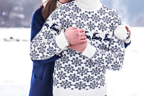 Loving couple in sweaters hugging, holding hands in the winter in nature