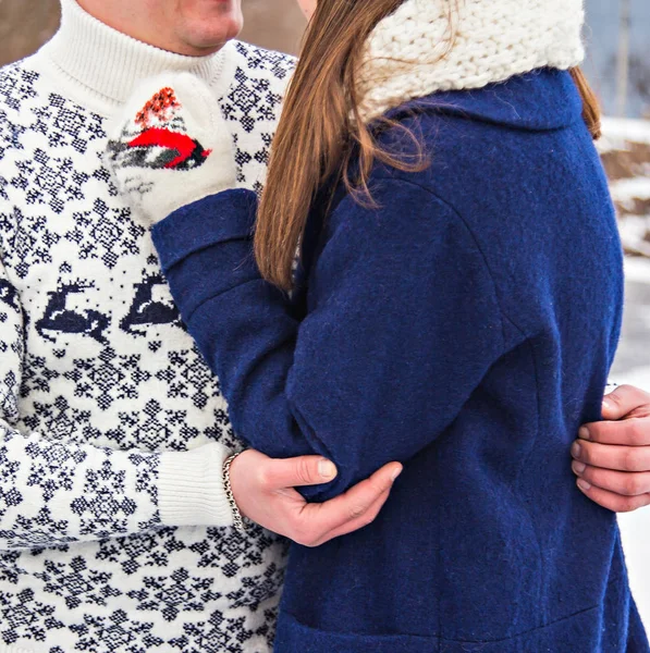 Loving couple in sweaters hugging, holding hands in the winter in nature