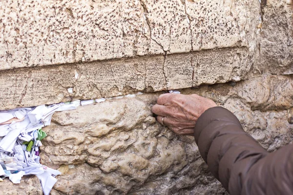 Mão de mulher orante no Muro Ocidental em Jerusalém. Uma velha toca uma pedra sagrada em oração . — Fotografia de Stock