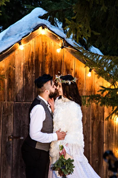 Pareja recién casada, novia y novio en el fondo de una antigua casa de madera y guirnalda retro . —  Fotos de Stock