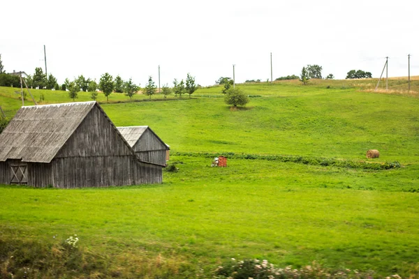 Zielona łąka, pastwisko i szary drewniany dom — Zdjęcie stockowe