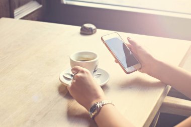 girl drinks espresso in a cafe and looks at a  phone