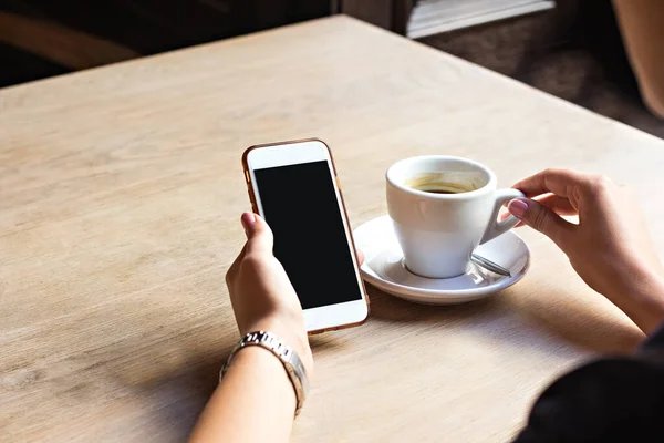Ragazza beve espresso in un caffè e guarda un telefono — Foto Stock