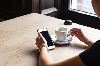 girl drinks espresso in a cafe and looks at a  phone