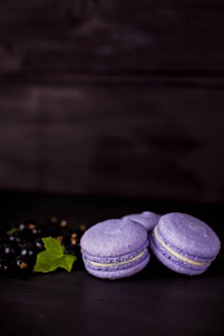 Macarons tanımlama karanlık bir arka plan üzerinde. Boş alan, seçici odak içeren koyu arka plan üzerinde renkli acıbadem kurabiyesi kurabiye ve tatlı kule