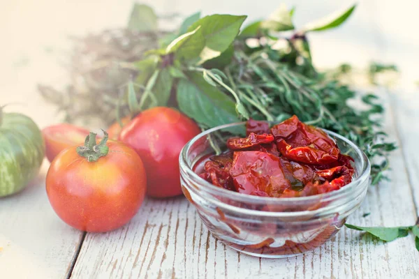 Sun dried tomatoes and aromatic herbs - thyme, basil, rosemary. Sun dried tomatoes with herbs and sea salt in olive oil in a glass jar