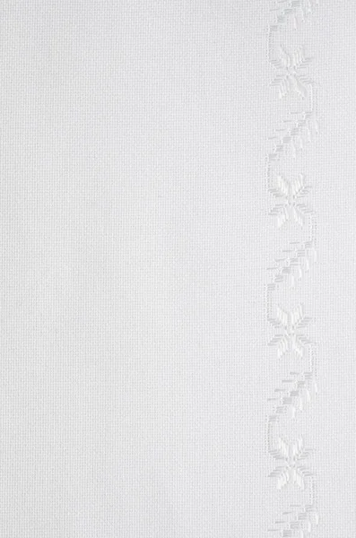 Текстура льняной ткани с белой шелковой вышивкой — стоковое фото