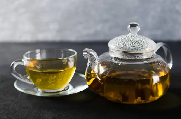 Copa de delicioso té de hierbas y tetera de vidrio . — Foto de Stock