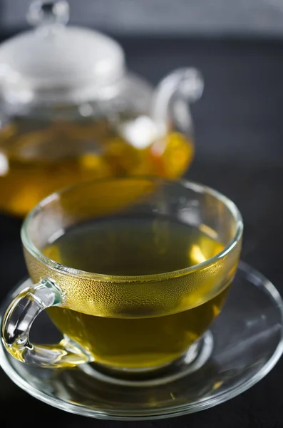 Copa de delicioso té de hierbas y tetera de vidrio . — Foto de Stock