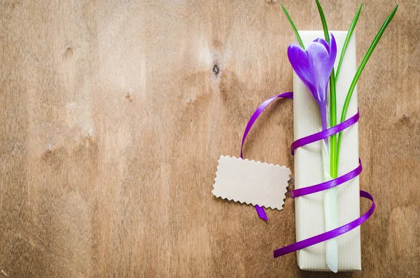 Present with fresh flower on wooden table.