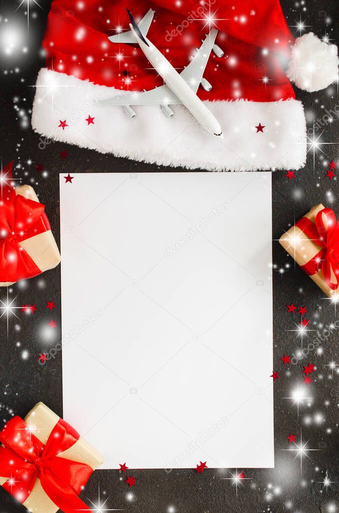 Trips or Christmas travel planning. Blank paper, toy airplane on Santa hat and gift boxes.