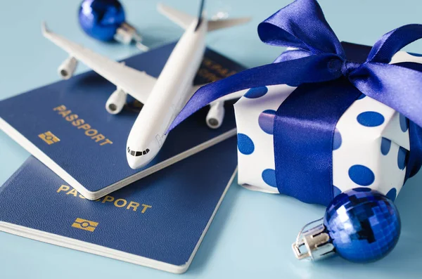Weihnachten oder Neujahr Reisekonzept. Spielzeugflugzeug mit Reisepässen und Geschenkbox auf blauem Hintergrund. — Stockfoto