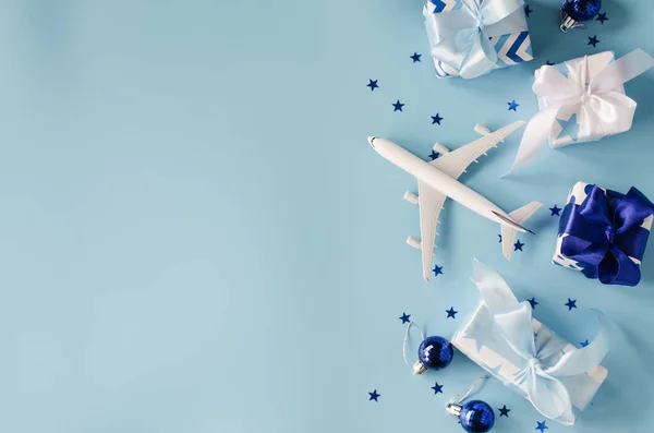 Vánoční nebo novoroční koncept cestování. Hračkové letadlo s pasy a dárkovými krabicemi na modrém pozadí. — Stock fotografie