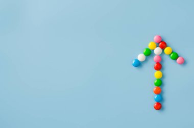 Mavi arka planda renkli sır ile çikolata şeker işaretçi ok.