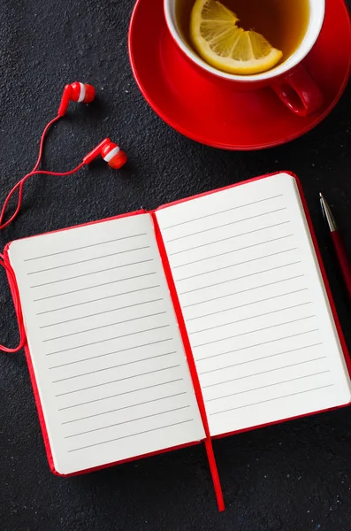 Порожній червоний блокнот, комп'ютерний ноутбук, навушники та чашка чаю. Концепція бізнесу або освіти . — стокове фото