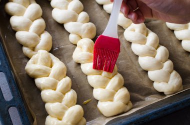 Hazırlık süreci - çiğ unbaked çörekler. Dişi el pişirmeden önce bir yumurta ile çiğ çörekler yağlar.