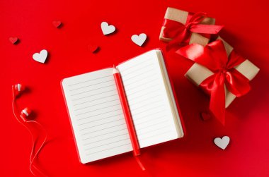 Kırmızı defter, hediye kutuları, tahta kalpler, kalem ve kulaklıklar..