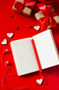 Kırmızı defter, hediye kutuları, tahta kalpler, kalem ve kulaklıklar..