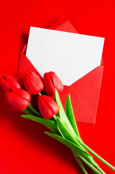 Red envelope with blank white paper and bouquet of tulips.