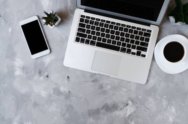 Ofis masasında siyah ekranlı, laptoplu, beyaz akıllı telefon ve bir fincan kahve. Telefonun taklidi..