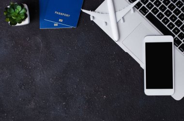 Seyahat rezervasyonu konsepti. Laptop, pasaportlar, akıllı telefon ve arka planda uçak modeli.