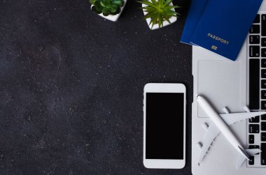 Seyahat rezervasyonu konsepti. Laptop, pasaportlar, akıllı telefon ve arka planda uçak modeli.