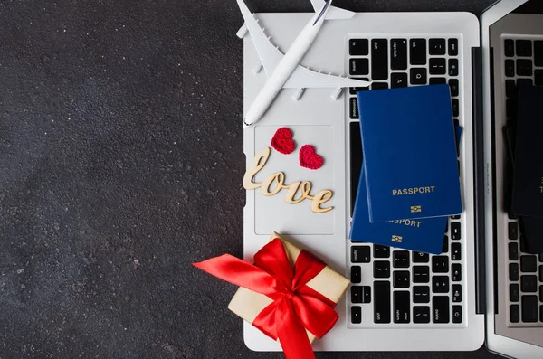 Planejamento de viagens no dia dos namorados. Conceito de viagem. Modelo de avião, laptop, passaportes e caixa de presente no fundo escuro . — Fotografia de Stock