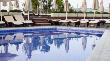 Boş güneşlik ve yüzme havuzu yakınında şemsiyeler. Plaj sandalyeleri tropik tatil köyü cennetinde. Tatil kavramı.
