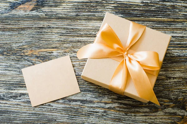 Caja de papel artesanal de regalo con cinta de lazo y etiqueta en blanco . — Foto de Stock