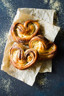 Fırında taze kokulu tarçınlı çörekler. Koyu arka planda geleneksel ev yapımı hamur işleri. Rustik stil.