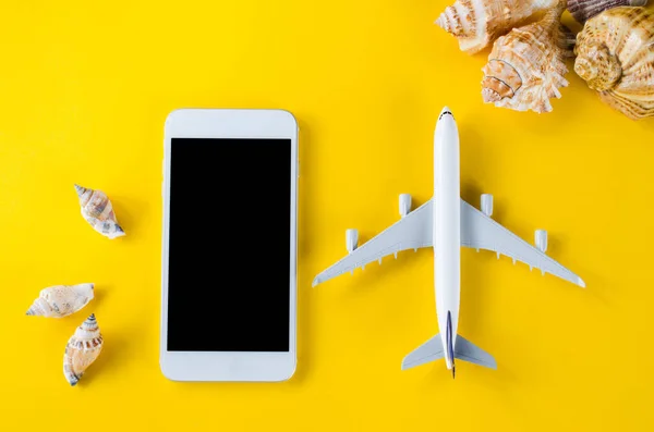 Empty screen smartphone, decorative airplane and seashells, template for app presentation.