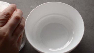 Kadın kuru yulaf ezmesini boş beyaz kaseye döker..