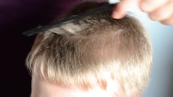 Женщина стрижет волосы мальчика дома. Домашняя стрижка . — стоковое видео