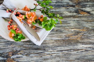 Rustik eskipli masada keten peçete üzerinde narin çiçeklerle vintage masa ayarı, yakın çekim. Çiçek dekoruna sahip Tatil Masa Seti