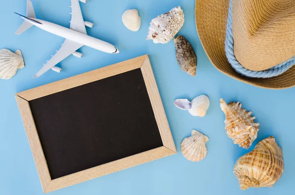 Empty chalkboard with seashells and inscription beach day on blue background. Summer vacation concept. Flat lay, top view. Copy space. Mock up.