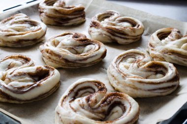 Çiğ pişmemiş çörekler. Pişirme kağıda ev yapımı geleneksel tarçın çörekler pişirmeye hazır. Rustik tarz. Geleneksel pasta
